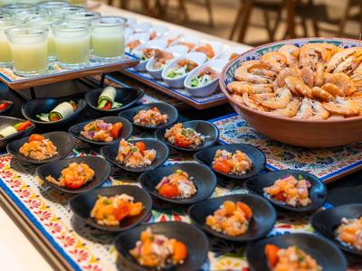Variedad de aperitivos y bebidas dispuestos en bandejas coloridas, ideal para un buffet de hotel.