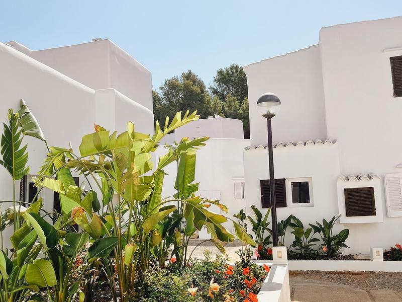 Biały budynek hotelu z zielonym ogrodem i niebieskim niebem w tle