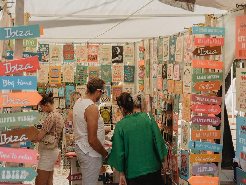 Kolorowy stragan z wieloma dekoracyjnymi drewnianymi tabliczkami i odwiedzającymi.