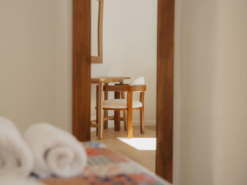 Widok przez drzwi na drewniany stół i krzesła w jasnym pokoju.
