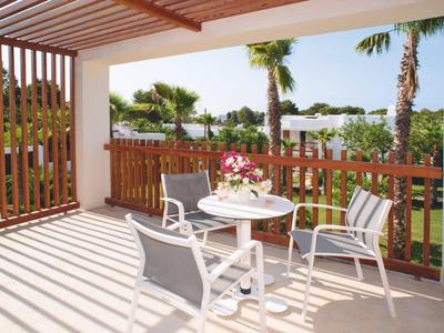 Terrasse mit überdachtem Sitzbereich, Tisch und Stühlen, umgeben von Holzgeländer und Palmen.