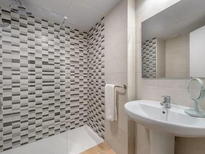 Nowoczesna łazienka z białą umywalką i czarno-białą wzorzystą ścianą prysznicową.