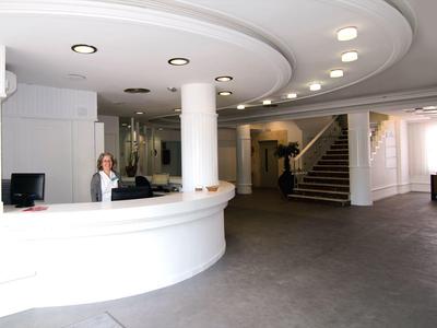 Recepcja z okrągłym białym biurkiem i pracownikiem w nowoczesnym hotelu.