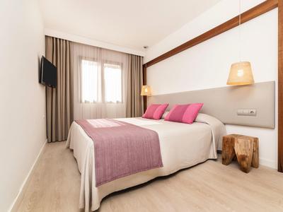 Moderne hotelkamer met tweepersoonsbed, paarse accenten en rustieke houten nachtkastjes.