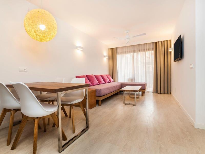 Moderne hotelkamer met eettafel, stoelen en slaapbank, licht en uitnodigend.