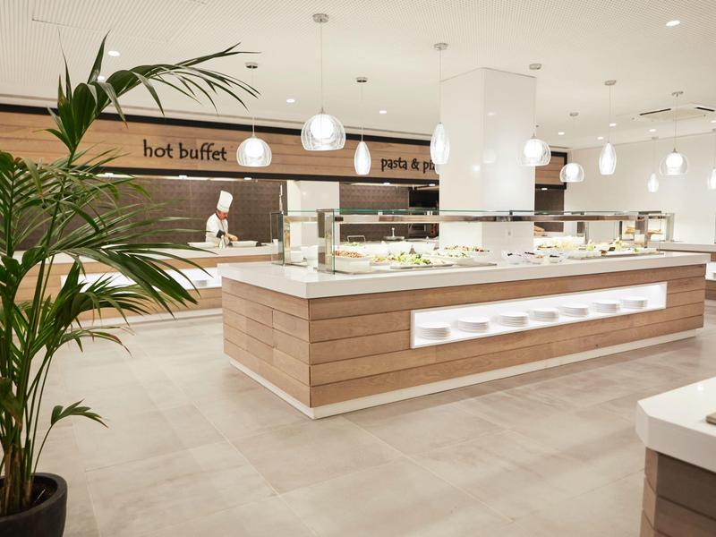 Buffetgedeelte met warme gerechten en moderne verlichting in een lichte eetzaal.