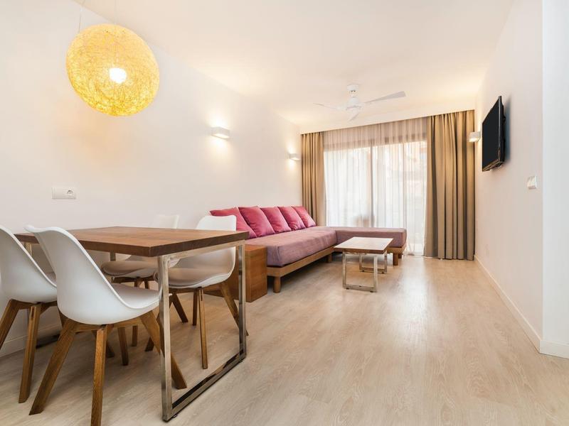 Moderne woonkamer met eethoek, slaapbank, houten vloer en grote raam met gordijnen.