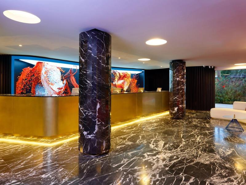 Nowoczesna recepcja z złotym kontuarem, czarnymi marmurowymi kolumnami i połyskującą marmurową podłogą.