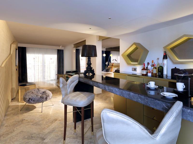Elegancki salon z marmurowym barem, wysokimi krzesłami i nowoczesnymi miejscami do siedzenia.
