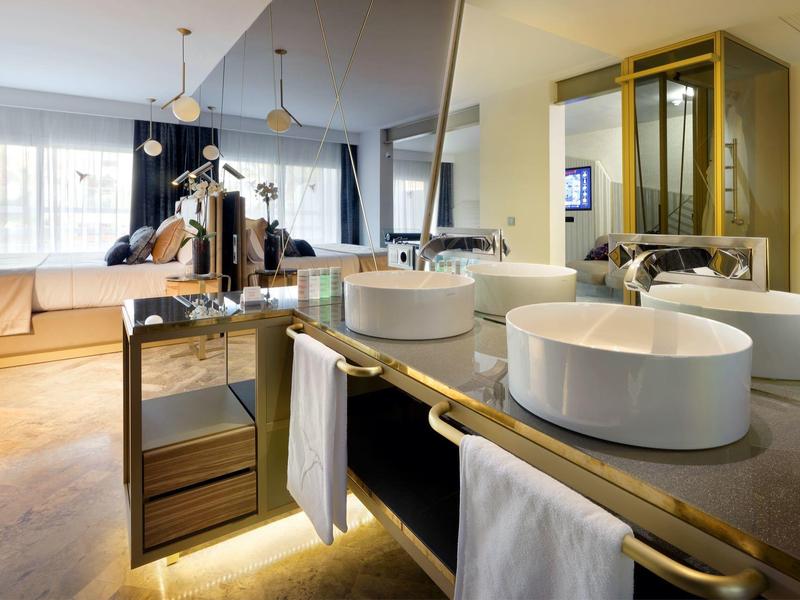 Nowoczesna łazienka z okrągłymi umywalkami, lustrem i dużą wanną przy oknie.