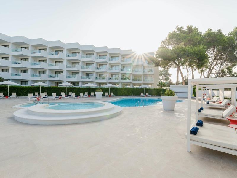 Nowoczesny basen hotelowy z jacuzzi, leżakami i drzewami o zachodzie słońca.