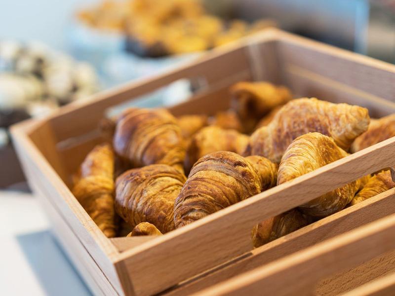 Drewniana skrzynia pełna świeżo upieczonych rogalików na stole.