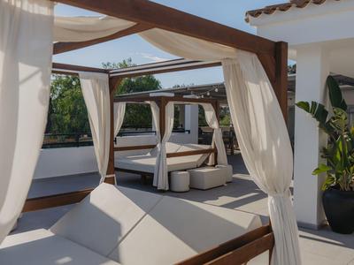 Moderne Dachterrasse mit weißen Daybeds, durchsichtigen Vorhängen und Pflanzen in Töpfen.