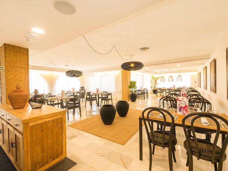 Licht restaurant met moderne houten meubels en veel stoelen en tafels voor gasten.