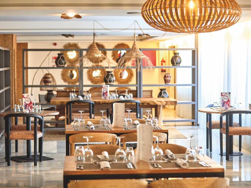 Licht, modern restaurant met houten meubels en decoratieve manden aan de muur.