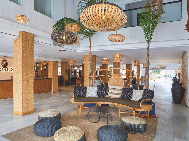 Moderne hotel lobby met zitplaatsen, planten en warme verlichting in een lichte setting.