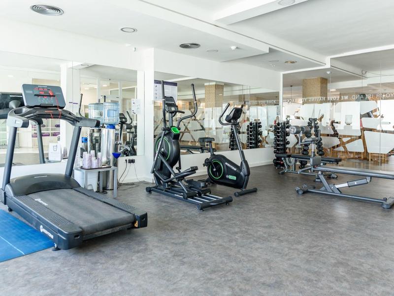 Lichte fitnessruimte in hotel met loopband, crosstrainer en gewichten.