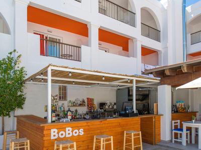 Moderne buitenbar genaamd BoBos met houten toonbank en verschillende barkrukken onder blauwe lucht.