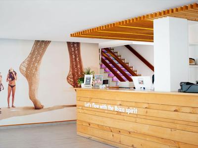 Moderner Empfangsbereich mit Holztheke und großer Wandgrafik eines Strandmotivs.