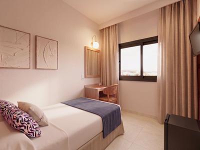 Lichte hotelkamer met bed, bureau, raam en minimalistische inrichting.