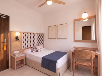 Gezellige eenpersoonskamer met bed, bureau, stoel en zachte verlichting.