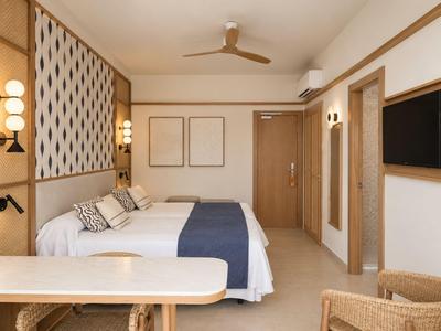 Modern hotelkamer met tweepersoonsbed, plafondventilator en aan de muur gemonteerde tv.