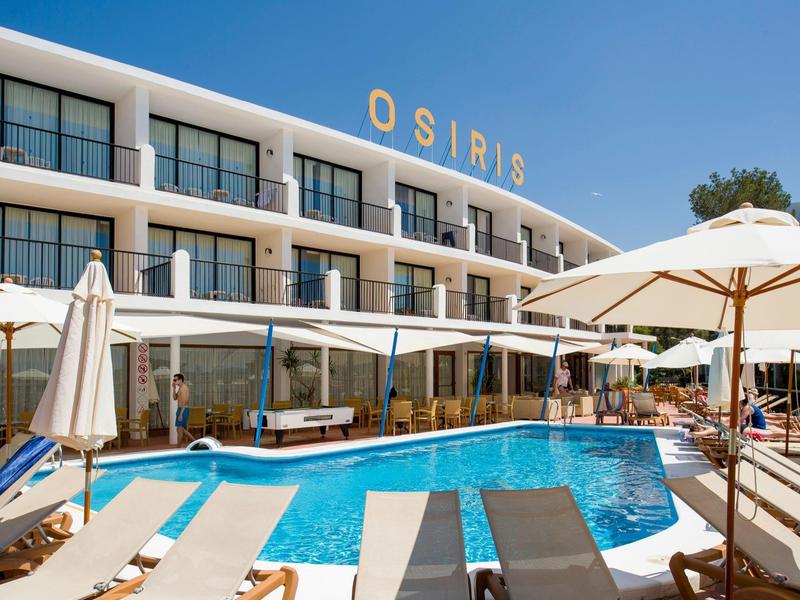 Modern hotel pool area with lounge chairs, umbrellas, and glass facade under clear sky