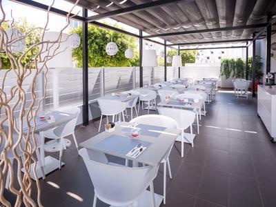 Modern covered outdoor terrace with white furniture in a hotel restaurant.