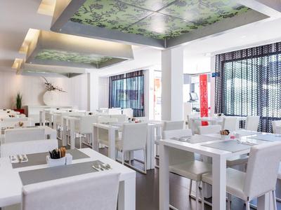 Bright, modern restaurant with white furniture and floral ceiling accents.