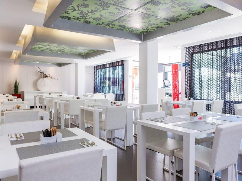 Bright, modern restaurant with white furniture and floral ceiling accents.