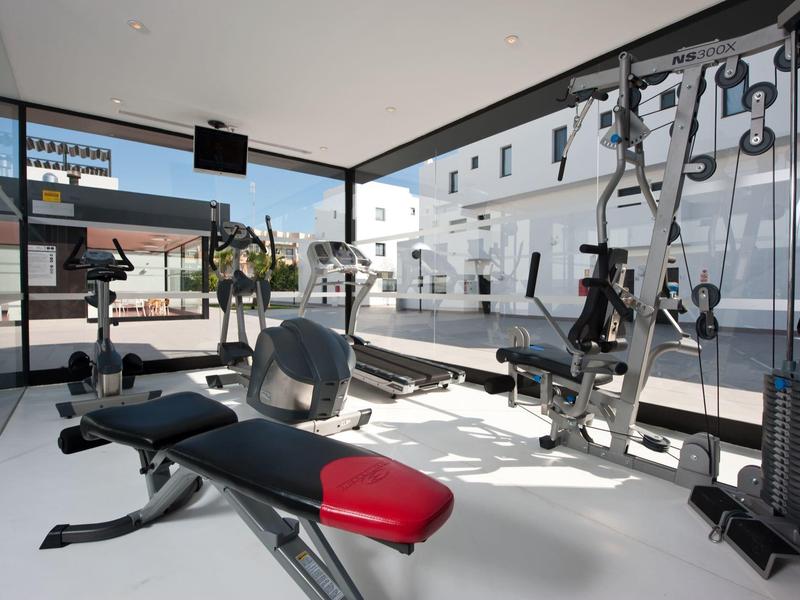 Modern gym equipment in a bright, open fitness room with large windows.