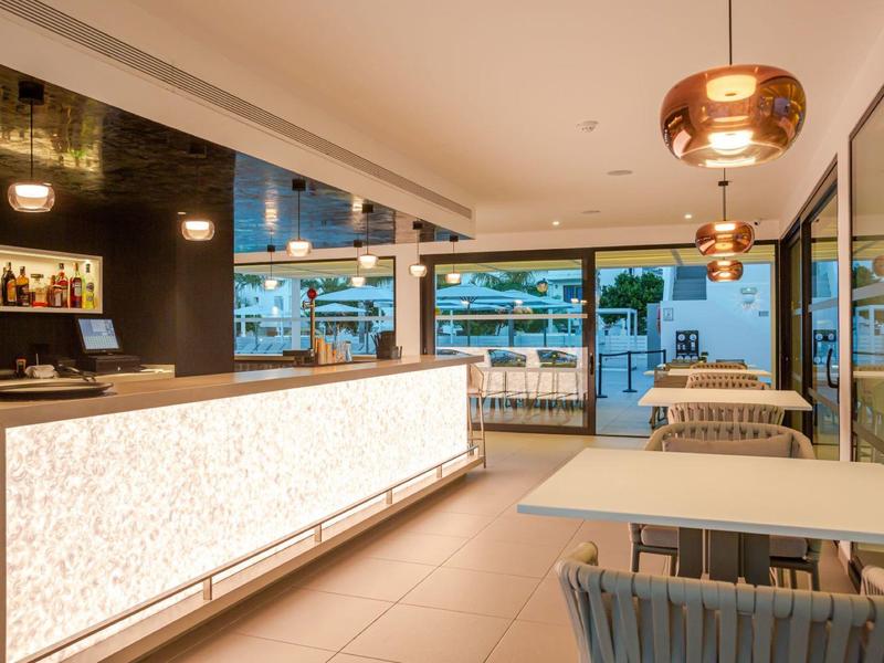 Modern hotel restaurant with illuminated bar and open seating areas overlooking outside.