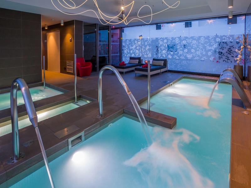 Modern indoor spa area with hot tub and pool in a luxury hotel.