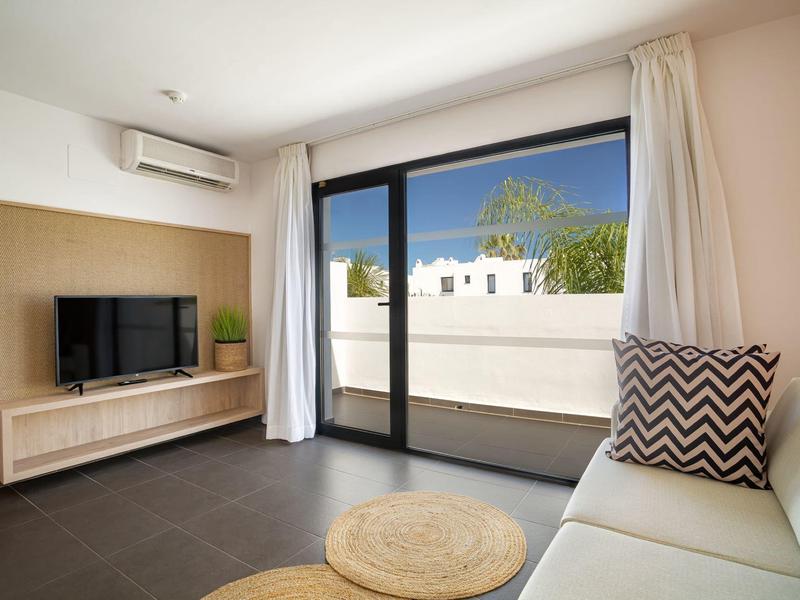 Modern living room with sofa, TV, and large glass sliding door to terrace.