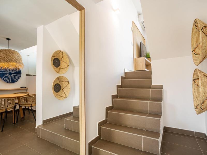 Modern interior with staircase and woven wall decor under warm lighting.