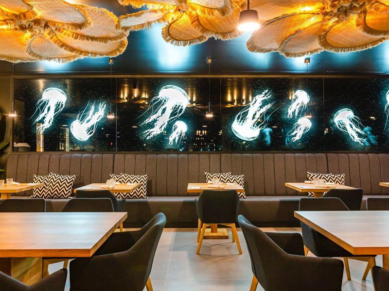 Modern restaurant with illuminated wall art and cozy seating areas.