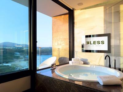 Luxury bathroom with a large round tub, towels, and a view through glass windows.