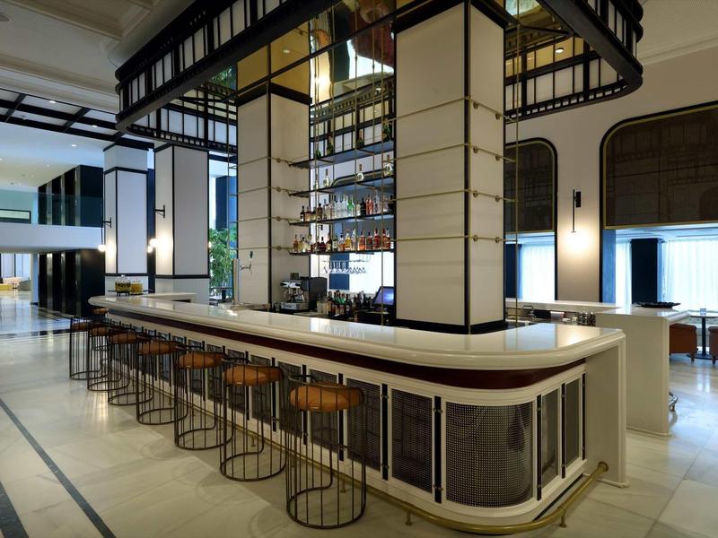 Modern hotel bar area with high stools, white countertop, and stylish interior lighting.