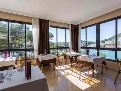 Heller Speiseraum mit großen Fenstern und Blick auf Wasser und Berge.