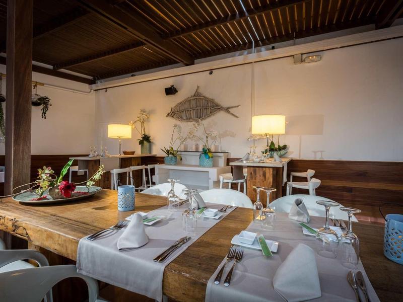 Elegantní jídelna s dřevěnými stoly, mořskými dekoracemi a teplým osvětlením.