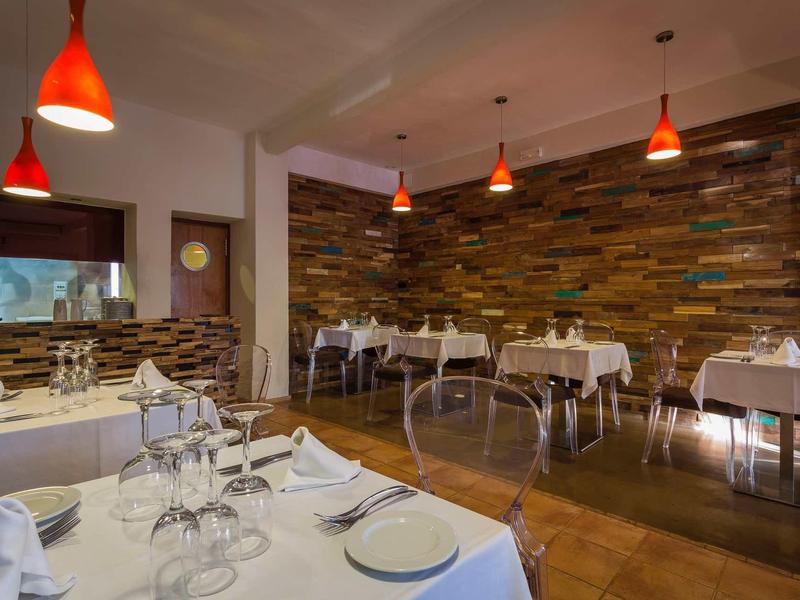 Elegantní restaurace s prostřenými stoly, kamennými zdmi a červenými závěsnými lampami.