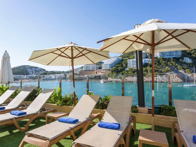 Lehátka s deštníky u moře, turistická přímořská krajina.