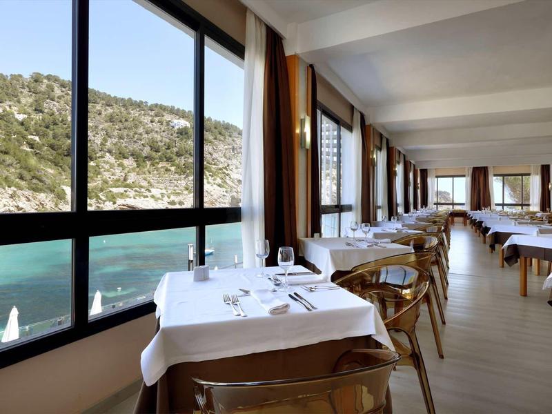 Jídelna s velkými okny s výhledem na moře a kopce.