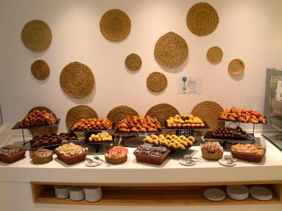 Buffet met verschillende gebakjes op een witte tafel tegen een muur met geweven ronde matten.