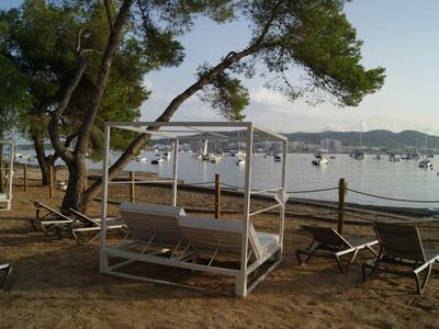 Gezellig dagbedgebied onder bomen met uitzicht op boten op het water.