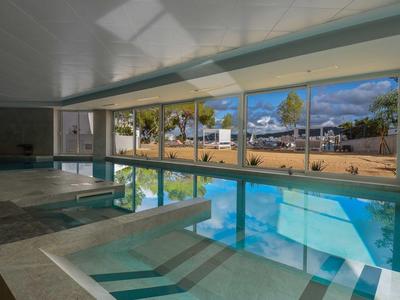 Binnenzwembad met grote panoramische ramen die uitkijken op zitgedeelte en buitenruimte.