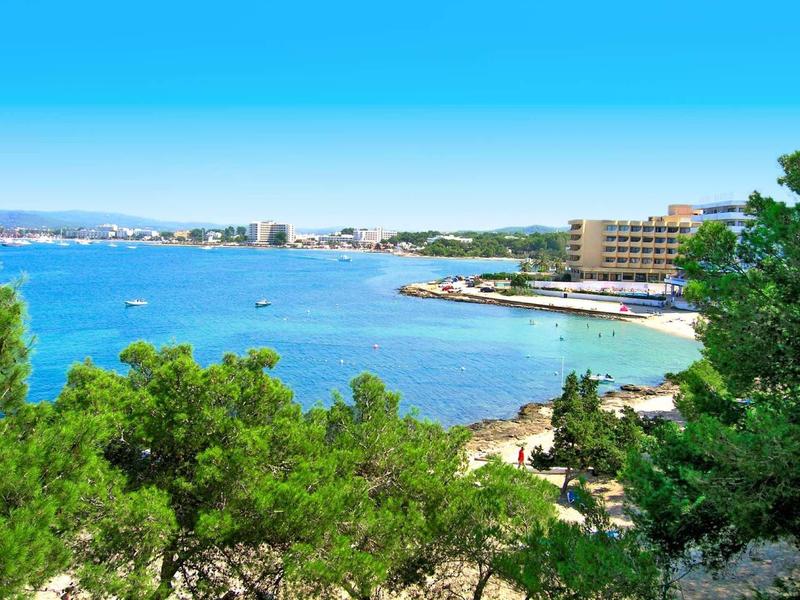 Kustlandschap met hotels en bomen onder een heldere blauwe lucht aan zee