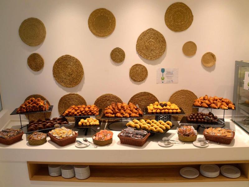 Buffet met verschillende gebakjes op een witte tafel tegen een muur met geweven ronde matten.