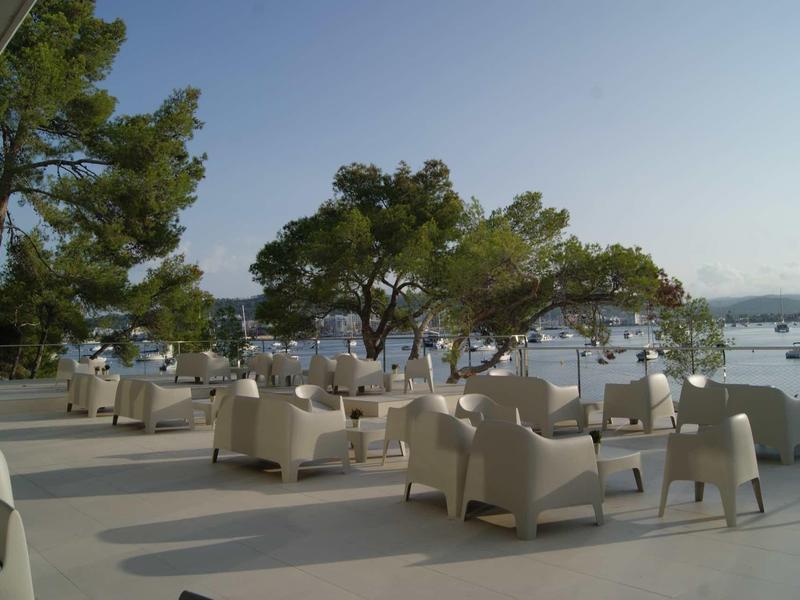 Buiten zithoek met witte fauteuils op een terras met uitzicht op water en boten.