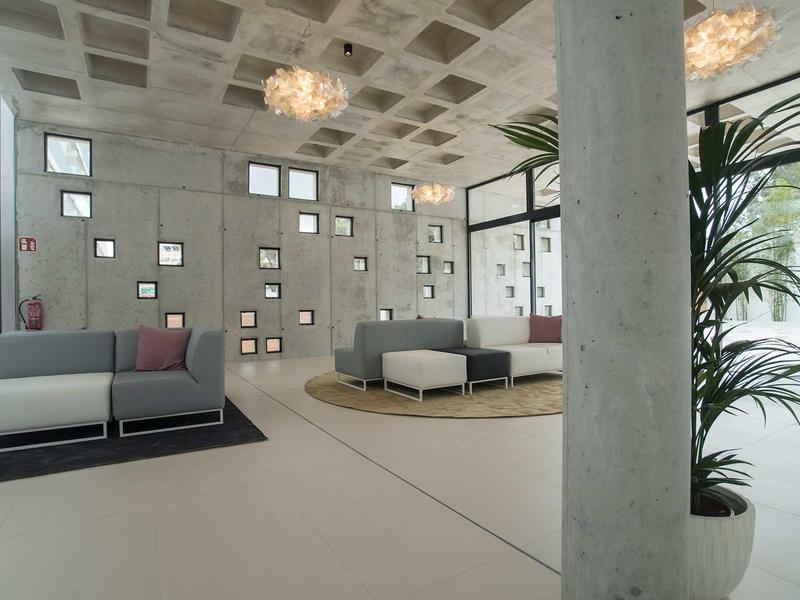 Moderne hotellobby met grijze sofa's, betonnen muren en grote ramen